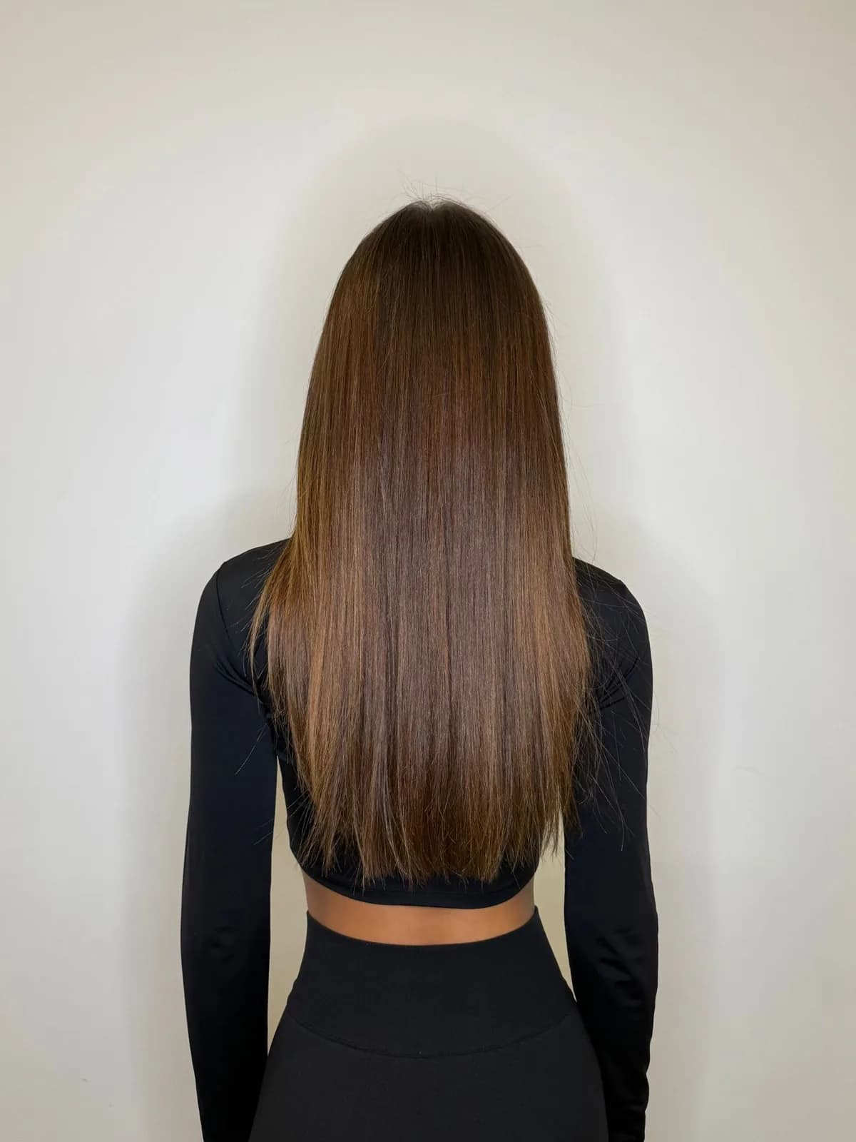 Longs cheveux lisses et brillants aux reflets châtain-caramel, couleur ravivée après un soin en salon