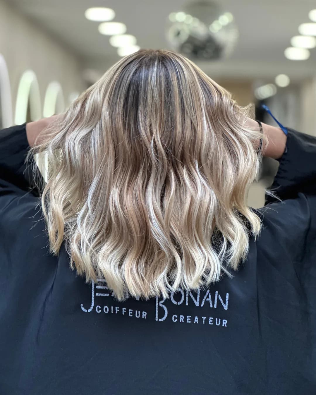 Coloriste à Luynes : chevelure blonde ondulée en balayage réalisée dans un salon Jean Bonan, vue de dos