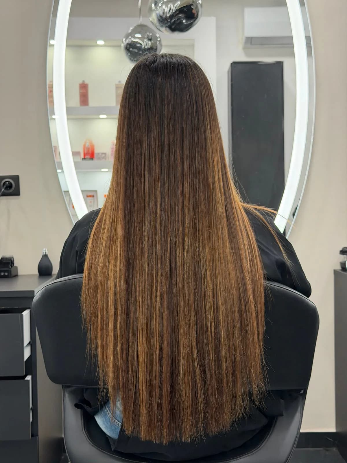 Balayage caramel Jean Bonan : longs cheveux lisses en dégradé brun-caramel, vus de dos